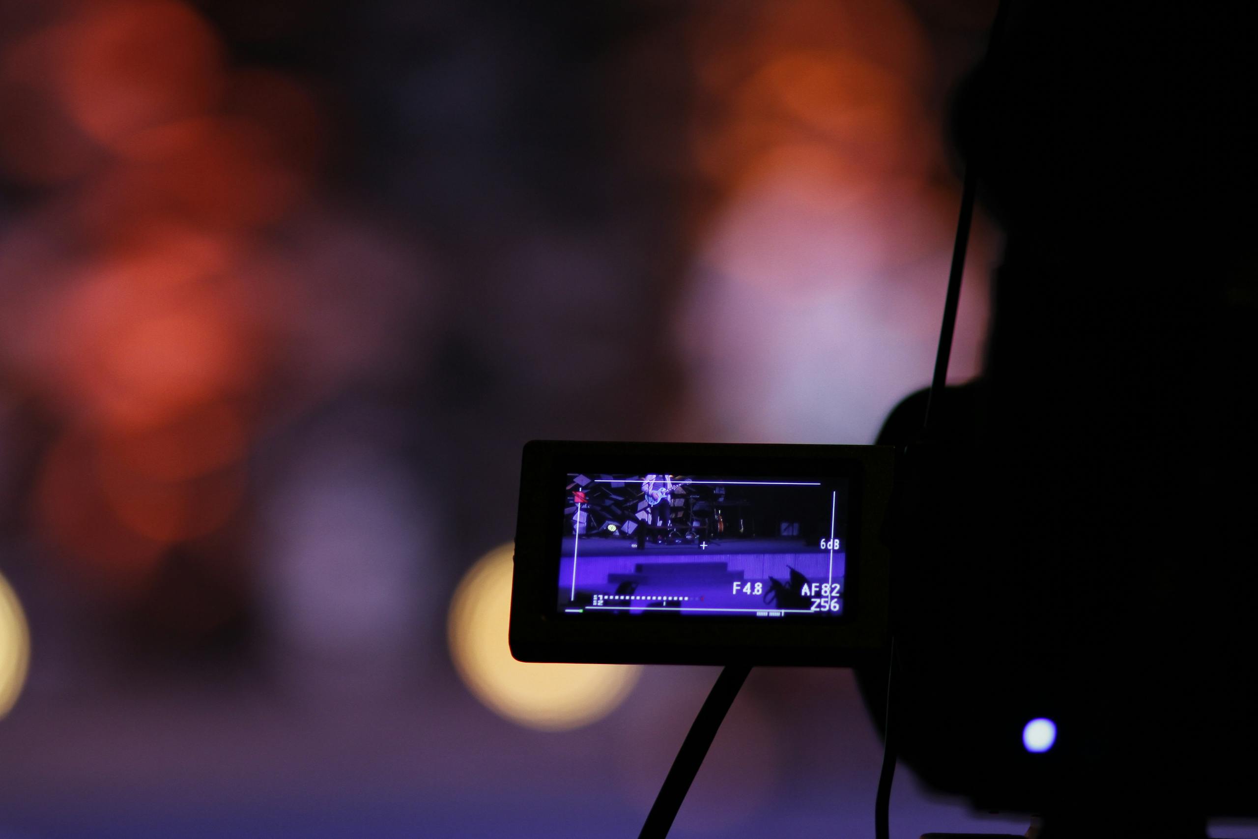 Close-up of a digital camera screen recording a scene with a vibrant bokeh background.